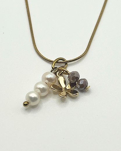 Goudkleurige ketting met drie bedels van parels, bloem en facetkralen